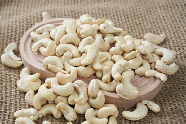 Premium Vietnam W320 cashew nuts arranged in a white bowl, showcasing their perfect crescent shape, uniform size, and flawless pale ivory color required for B2B export.