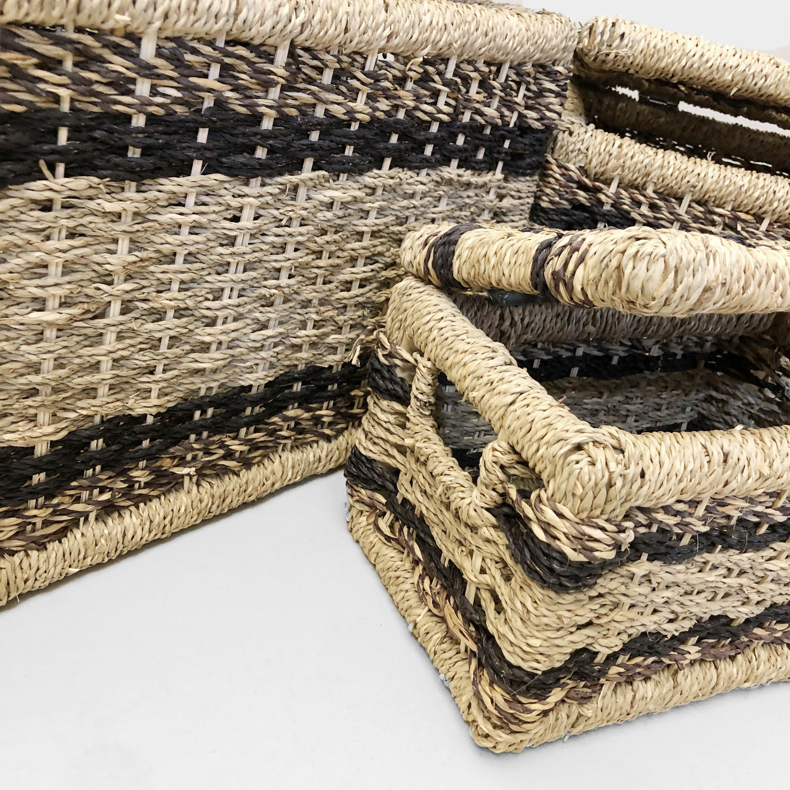 Close-up detail of natural seagrass basket weaving technique with black rope accents.