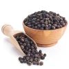 Organic Black Peppercorns overflowing from a wooden bowl and scoop.