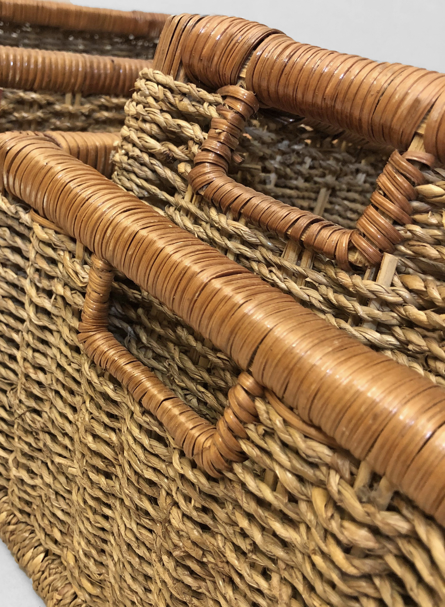 Detailed close-up of the integrated cut-out handle wrapped with natural Rectangular seagrass storage baskets on model PT.K55.